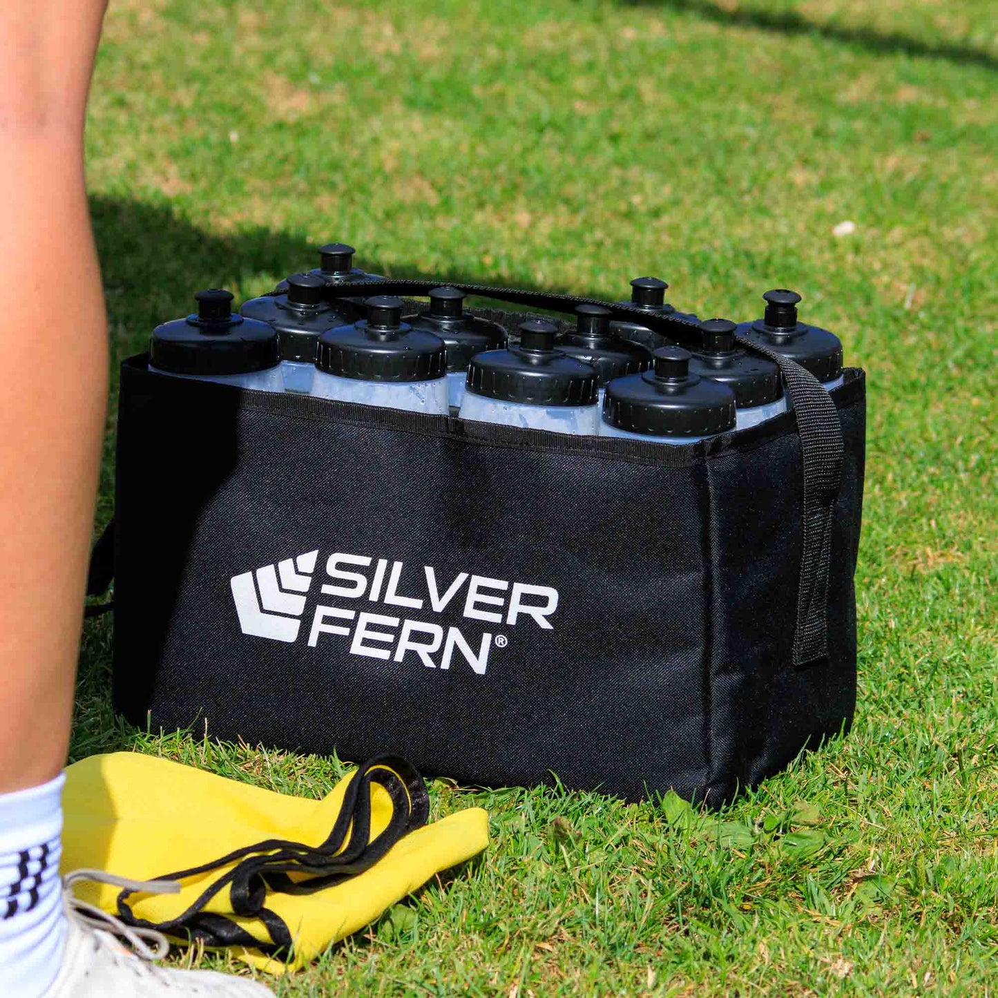 Drink bottle carrier fabric, 12 bottles capacity, bottle in drink carrier on field, lifestyle.