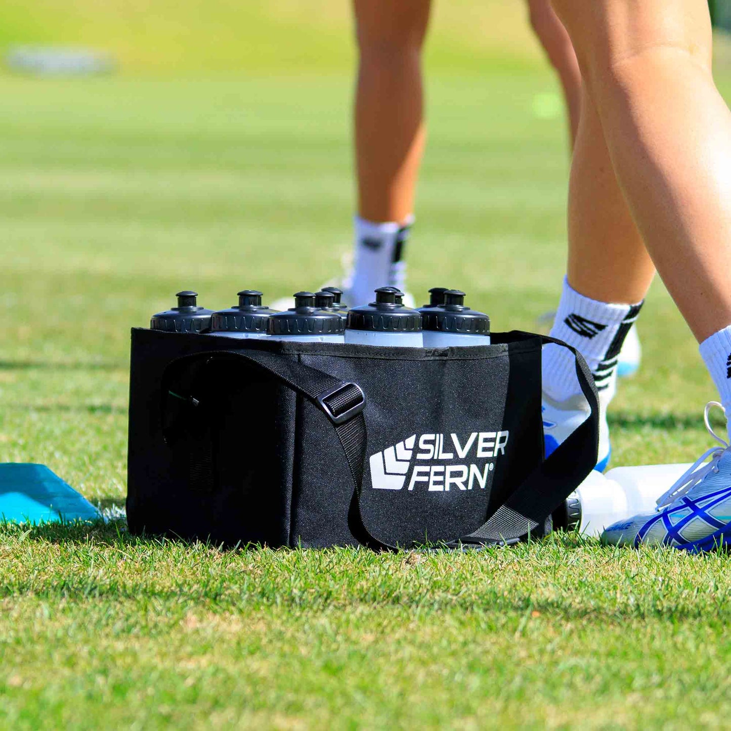 Drink bottle carrier fabric, 12 bottles capacity, bottle in drink carrier on field, lifestyle.