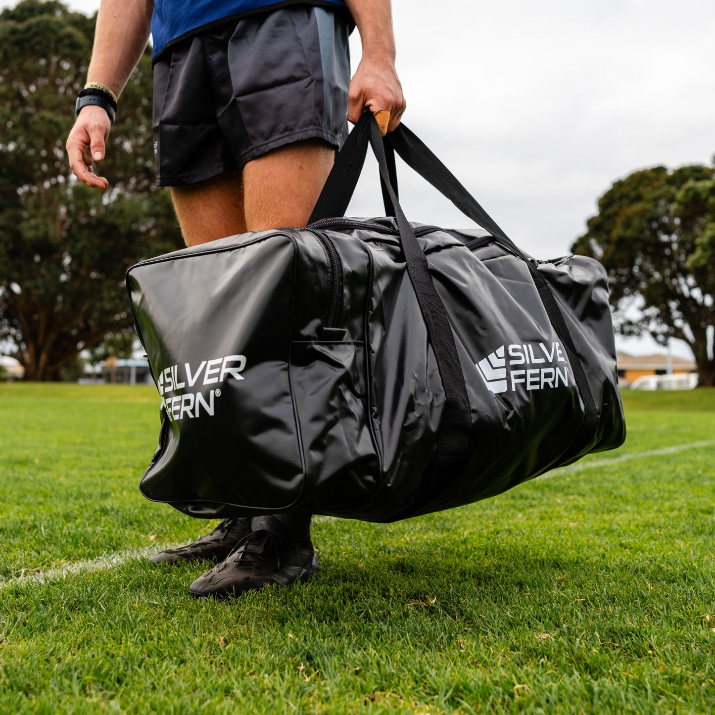 Silver Fern black PVC gear bag size large, lifestyle shot, rugby player holding the bag