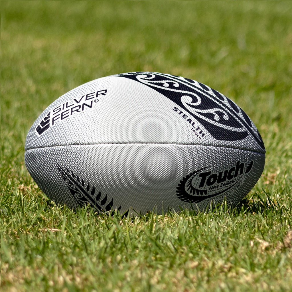 Silver Fern Touch Rugby Ball Stealth Match, Lifestyle shot, sitting on a rugby field