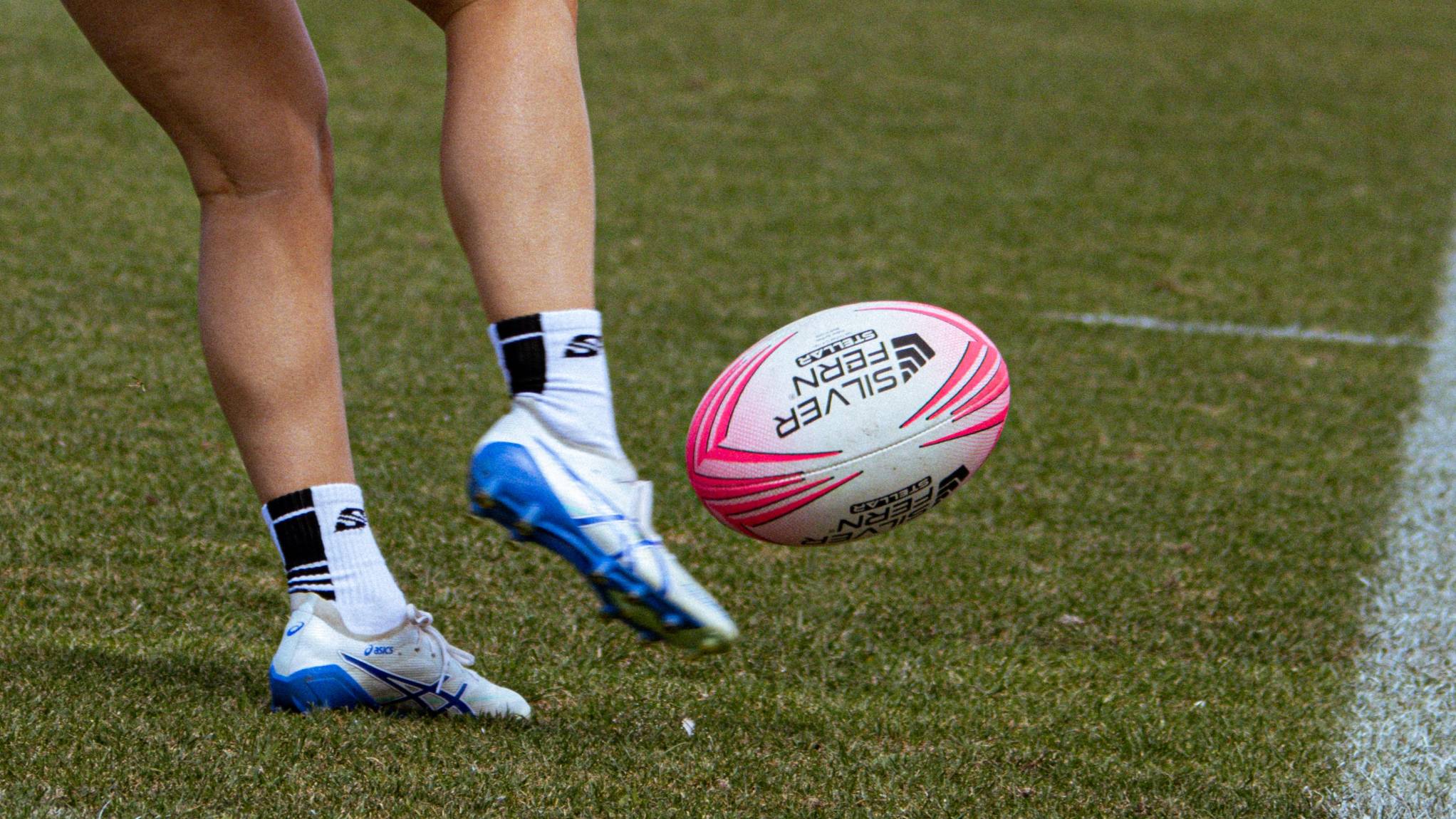 Silver Fern Stellar Premium Trainer Rugby Ball hero shot, horizontal action shot of ball being kicked by rugby player